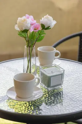 a table with two cups and a vase with flowers at Gamers' Paradise - Modern Apartment with Parking in Cracow by Noclegi Renters in Kraków