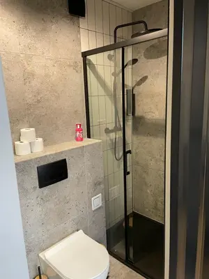 a bathroom with a toilet and a glass shower at Kontener 15G in Skawina