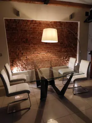 a glass table and chairs in a room with a brick wall at Apartament Deluxe w centrum Brzeska nr 2 in Brzesko