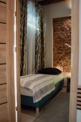 a small bedroom with a bed and a brick wall at Apartament Deluxe w centrum Brzeska nr 2 in Brzesko