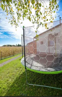 a trampoline in the grass next to a building at Dom z jacuzzi & tarasem całoroczny do 10 osób DOM NA PROMOWEJ - LAS, Zator in Zator