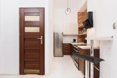 a kitchen with a refrigerator and a wooden door at Kazimierz - 34 Dietla street in Kraków