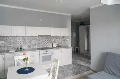 a kitchen with white cabinets and a table with a vase on it at Apartament Róża 2 Zator - 2km od Energylandii in Zator