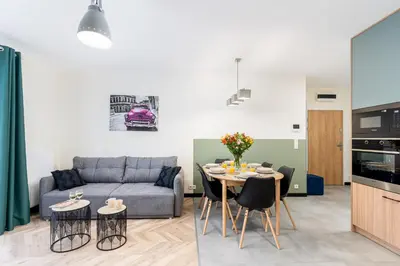 a living room with a couch and a table with chairs at Saska Park Apartments in Kraków