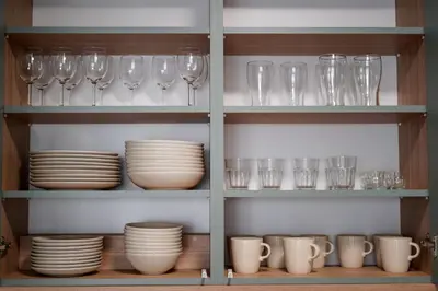 a shelf filled with glasses and plates and cups at Saska Park Apartments in Kraków
