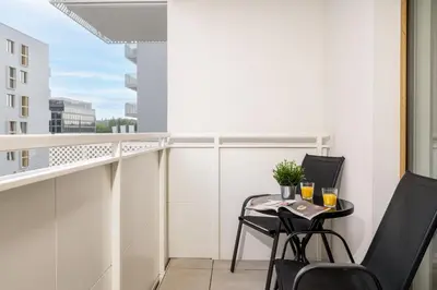 a balcony with two chairs and a table with drinks on it at Saska Park Apartments in Kraków
