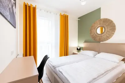 a bedroom with a bed with yellow curtains and a mirror at Saska Park Apartments in Kraków