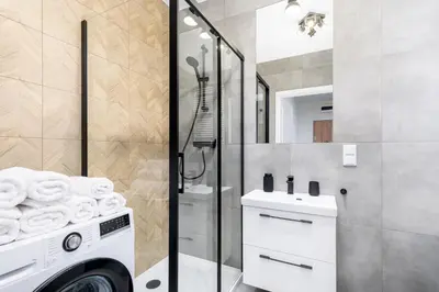 a bathroom with a washing machine and a shower at Saska Park Apartments in Kraków