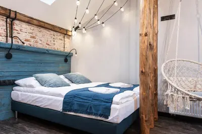 a bedroom with a bed with a blue headboard and lights at Kazimierz District - Dietla 51 street in Kraków