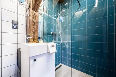a bathroom with a toilet and a shower with blue tiles at Kazimierz District - Dietla 51 street in Kraków
