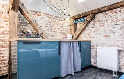 a kitchen with blue cabinets and a brick wall at Kazimierz District - Dietla 51 street in Kraków