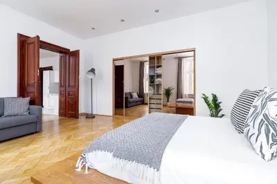a white bedroom with a bed and a living room at Two Bedroom Apartment - Dietla 51 street in Kraków