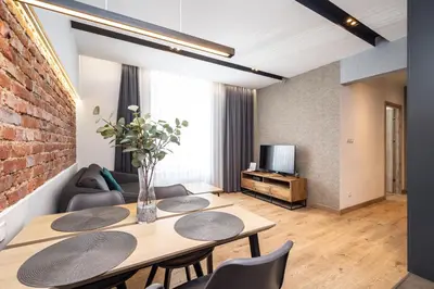a living room with a table and chairs and a brick wall at RentPlanet - Apartament Prusa in Kraków