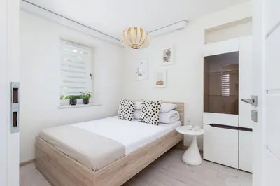 a white bedroom with a bed and a chandelier at One bedroom apartment in the centre - Sarego 16 in Kraków