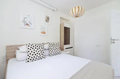 a white bedroom with a white bed with black and white pillows at One bedroom apartment in the centre - Sarego 16 in Kraków