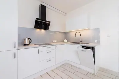 a white kitchen with white cabinets and a sink at One bedroom apartment in the centre - Sarego 16 in Kraków