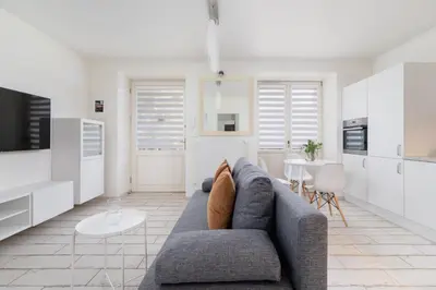 a living room with a gray couch and a kitchen at One bedroom apartment in the centre - Sarego 16 in Kraków