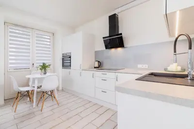 a kitchen with white cabinets and a table and chairs at One bedroom apartment in the centre - Sarego 16 in Kraków