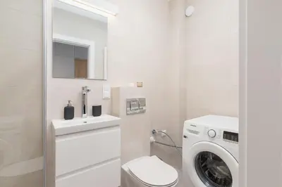 a white bathroom with a washing machine and a washer at Apartment with balcony Kalwaryjska 34 street in Kraków