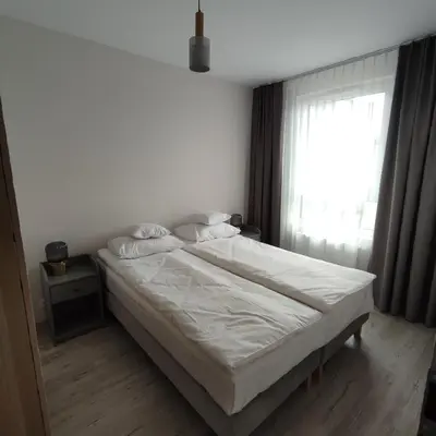 a bedroom with a white bed and a window at Apartamenty przy Mogilskiej z miejscem postojowym in Kraków