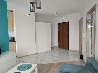 a living room with a blue couch and a wooden door at Apartamenty przy Mogilskiej z miejscem postojowym in Kraków