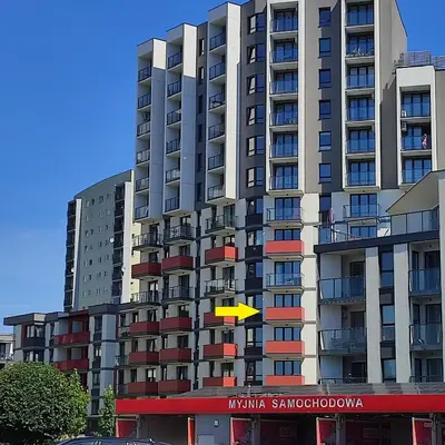 a tall building with a yellow sign in front of it at Apartamenty przy Mogilskiej z miejscem postojowym in Kraków
