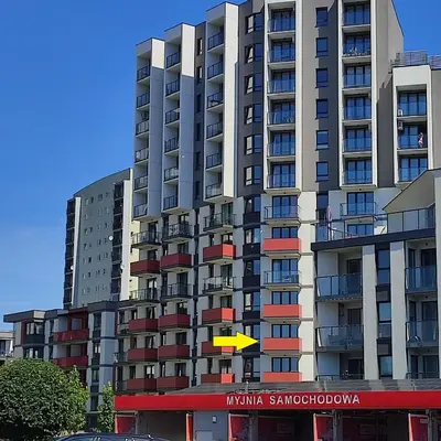 a tall apartment building with a yellow sign in front of it at Apartamenty przy Mogilskiej z miejscem postojowym in Kraków
