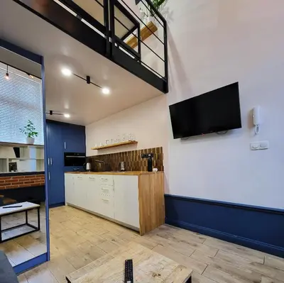 a living room with a kitchen with a tv on the wall at Przystań na Kazimierzu in Kraków