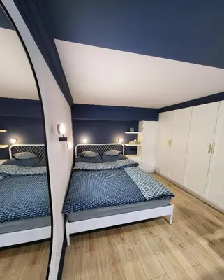 two beds in a bedroom with blue walls and wooden floors at Przystań na Kazimierzu in Kraków