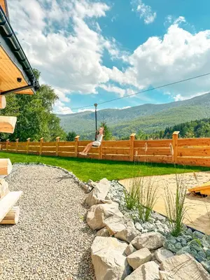 a woman sitting on a fence looking at the mountains at Bale na Skale Chata & SPA-Zawoja in Skawica