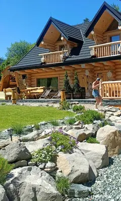 a woman taking a picture of a log house at Bale na Skale Chata & SPA-Zawoja in Skawica