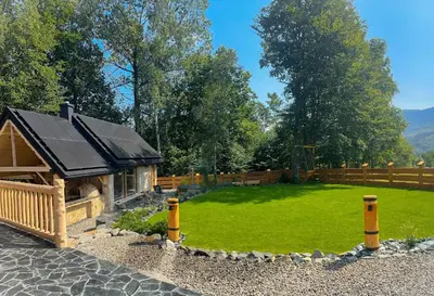 a large yard with a wooden cabin with a green lawn at Bale na Skale Chata & SPA-Zawoja in Skawica