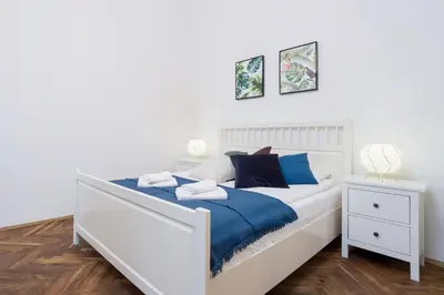 a white bedroom with a bed and a nightstand at Apartment with City View - Dietla 68 street in Kraków