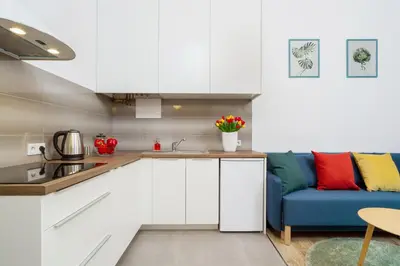 a kitchen with white cabinets and a blue couch at Apartment with City View - Dietla 68 street in Kraków