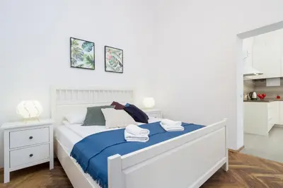 a bedroom with a white bed with blue sheets at Apartment with City View - Dietla 68 street in Kraków