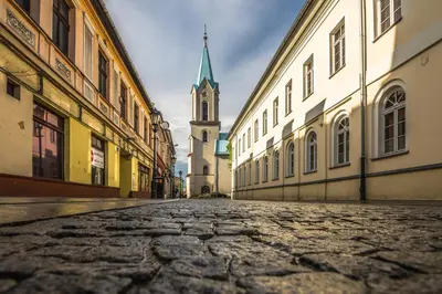 an empty street with a clock tower in the distance at Apartament Powstańców 19 in Oświęcim