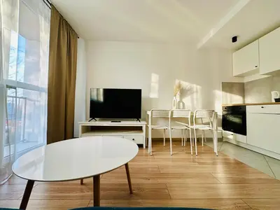 a white living room with a table and a tv at Apartament Powstańców 19 in Oświęcim
