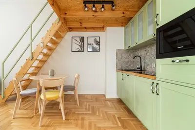 a kitchen with green cabinets and a table with a yellow chair at Apartment with balcony - Dietla 109 street in Kraków