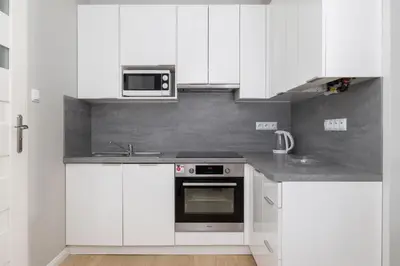 a white kitchen with white cabinets and a microwave at 3-bedroom apartment - Old Town- Blich 9 in Kraków
