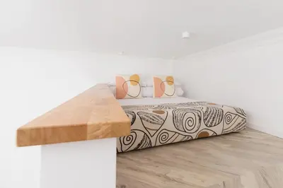 a white bedroom with a bed with a wooden table at Main Square - Modern Apartment - 7 Gertrudy street in Kraków
