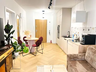 a kitchen and living room with a table and chairs at Charming Apartment in a green area- free parking in Kraków