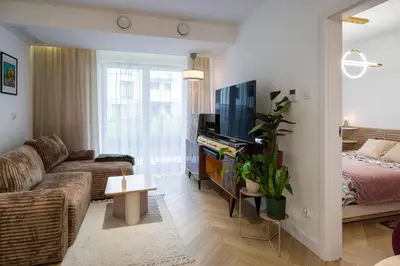 a living room with a couch and a bed at Charming Apartment in a green area- free parking in Kraków
