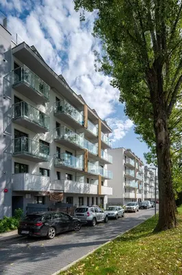 a parking lot with cars parked in front of a building at Charming Apartment in a green area- free parking in Kraków