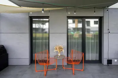 a table with orange chairs and a table with a vase at Charming Apartment in a green area- free parking in Kraków
