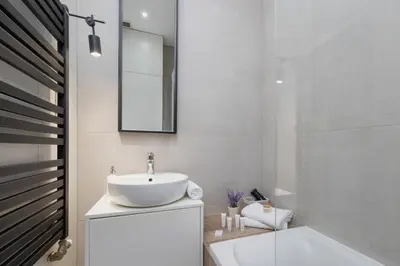 a bathroom with a sink and a mirror and a tub at Studio z Klimatyzacją na Krakowskim Kazimierzu by Noclegi Renters in Kraków