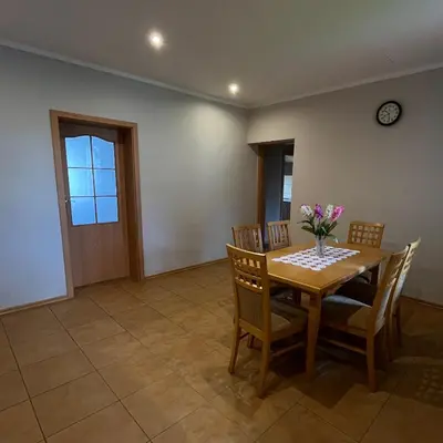 a dining room with a table and chairs and a clock at Pogodny Dom in Włosienica