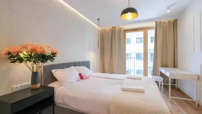 a bedroom with a bed and a desk with a vase of flowers at Luxury apartment Free parking - by Hosty in Kraków