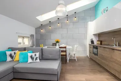 a living room with a gray couch and a kitchen at 2-Bedroom Apartment - Sarego 16 in Kraków
