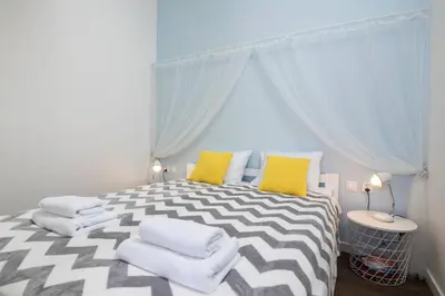 a bedroom with a large bed with yellow and white pillows at 2-Bedroom Apartment - Sarego 16 in Kraków