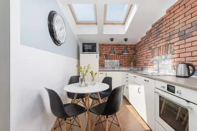 a kitchen with a table and chairs and a clock on the wall at 3-Bedroom apartment in the centre - Old Town in Kraków